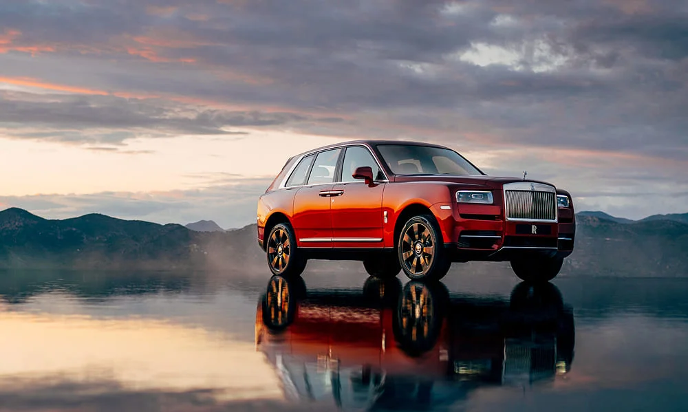 Luxury Rolls-Royce Cullinan on a reflective landscape at golden hour